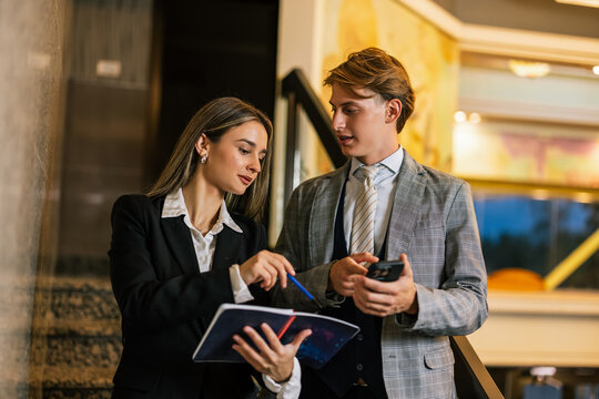 Business team walking down hotel staircase reviewing notes