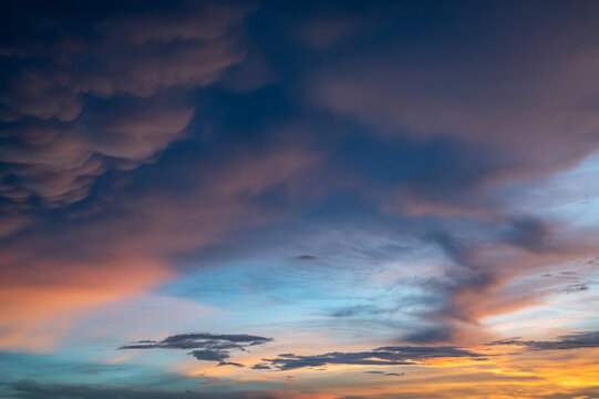 Dramatic Twilight Cloudscape Background, Deep Blue Sky with Pink Sunset Glow and Textured Mammatus Clouds at Dusk.