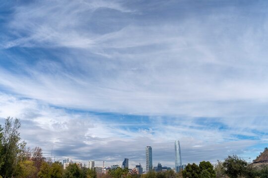 Cielo azul con nubes cirrus sobre el skyline de Santiago de Chile, la Gran Torre Santiago y el distrito financiero de Las Condes al horizonte