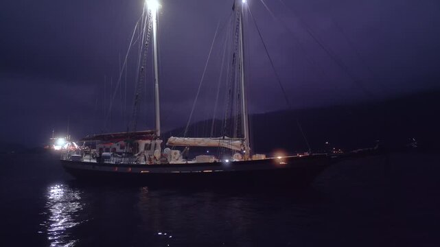 Big expeditional sailing boat anchored in the calm sea at night. Drone night shot