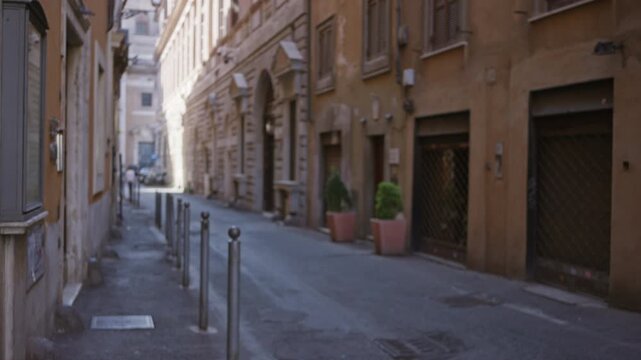 Narrow rome street with defocused shallow bokeh, soft blurred buildings and bollards; background backplate template calm.