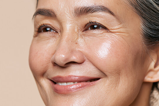 Radiant middle aged Japanese woman close up portrait with smooth glowing skin, smile lines and natural makeup conveying warmth and confidence