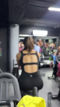 Woman working out in gym from behind wearing black activewear