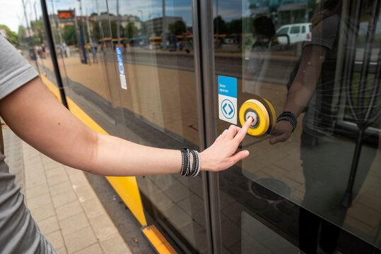 Visually impaired woman's hand pressing the door open button on a tram