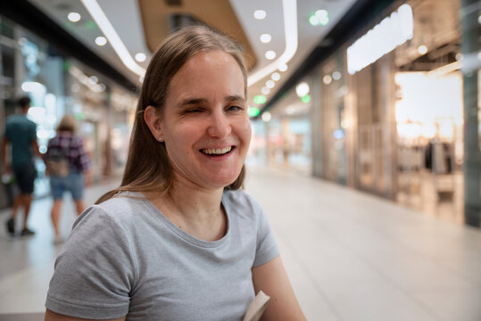 Close-up portrait of a blind blond haired woman cheerful smiling while sitting in a shopping mall