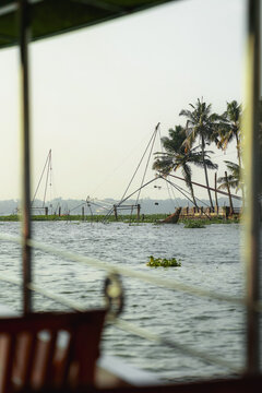 View of traditional Chinese fishing nets along the backwaters with palm trees in the background in Kochi, Kerala, India.
