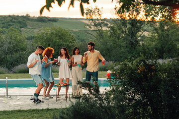 Obraz premium Friends celebrating poolside, enjoying summer cocktails and lively conversation during a sunset social event
