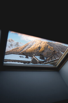 View of snow-covered mountains and rooftops seen through a skylight in winter in Chamonix, Auvergne-Rhone-Alpes, France.