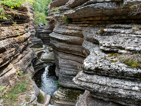 View of the layered limestone rock formations of the Rosomacka Reka canyon with a small stream flowing through the narrow gorge in Rosomac, Pirot District, Serbia.