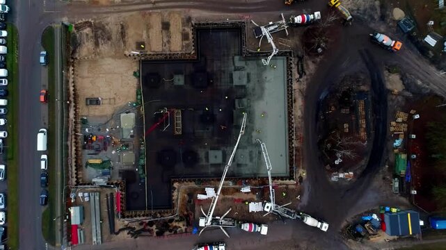 Aerial view of a construction site at Riga Port with concrete mixers and pump trucks pouring concrete into a foundation in Riga, Latvia.