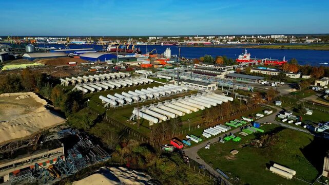 Aerial view of the industrial storage tanks and port infrastructure at Riga Port, featuring rows of white cylinders and shipping facilities along the Daugava River in Riga, Latvia.