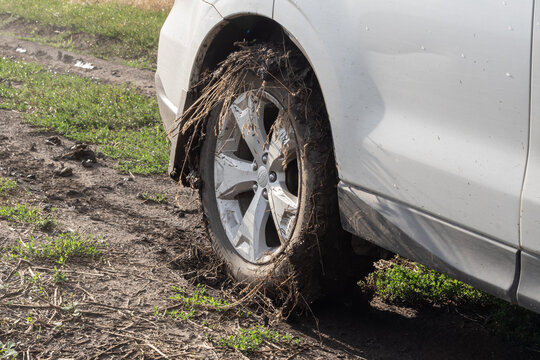 Sport utility vehicle covered with mud driving on a rural dirt road. Off road transportation, countryside travel and challenging terrain.