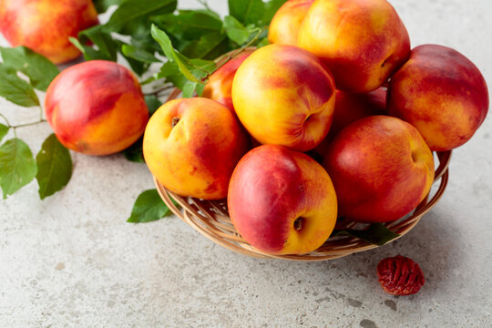 Fresh nectarines with leaves on a kitchen table.