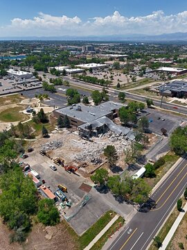 Aerial view of a building demolition site with heavy machinery and debris in Thornton, Colorado, United States.