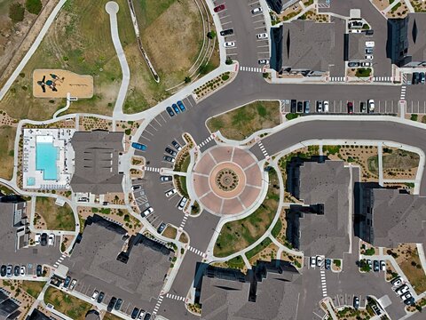 Aerial view of a residential complex featuring a central roundabout, parking lots, apartment buildings, and a swimming pool in Thornton, Colorado, United States.