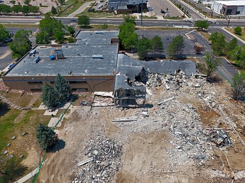 Aerial view of a building demolition site with piles of rubble and debris next to a partially destroyed structure in Thornton, Colorado, United States.
