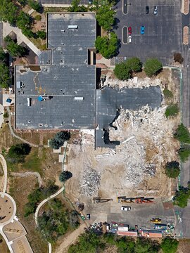 Aerial view of a building demolition site with heavy machinery, debris, and partial structure remaining in Thornton, Colorado, United States.
