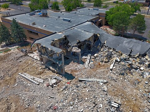 Aerial view of a partially demolished building with exposed structural elements, debris, and rubble in a suburban area Thornton, Colorado, United States.