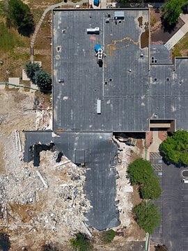 Aerial view of a building demolition site with heavy machinery, debris, and exposed structural elements in Thornton, Colorado, United States.