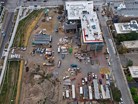Aerial view of an active construction site featuring heavy machinery, building materials, and a partially completed structure in Boulder, Colorado, United States.