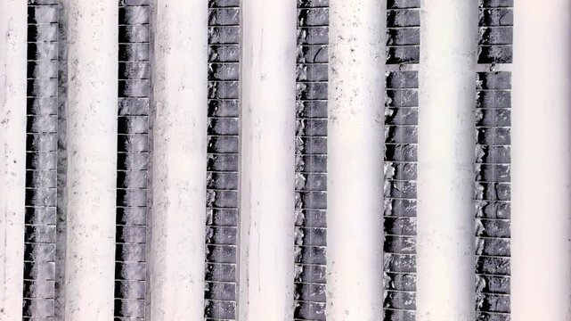 Aerial view of white architectural columns alternating with dark textured grid panels in Latvia.