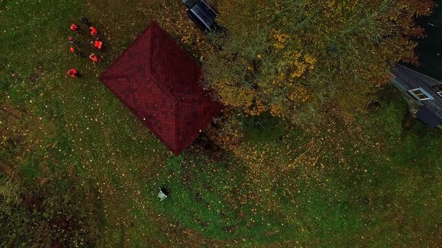 Aerial view of a red roof building surrounded by a grassy lawn covered in fallen autumn leaves in Latvia.