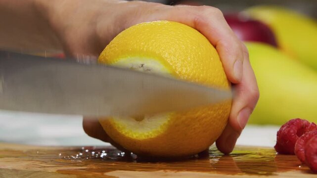 Extreme closeup of knife slicing through juicy orange