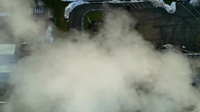 Aerial view of thick steam rising over a parking lot with patches of snow in Riga, Latvia.