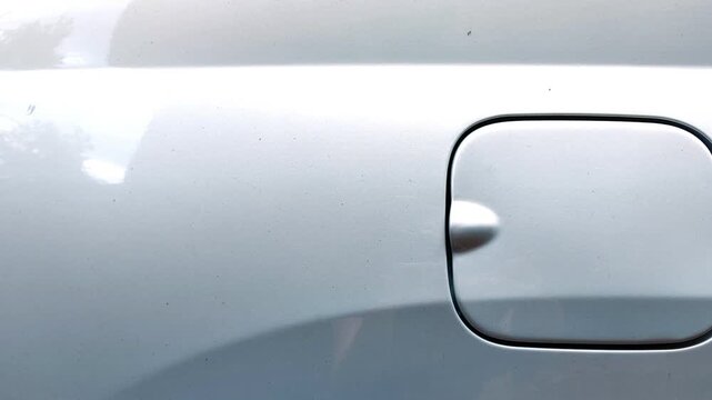 Close up of a light green sedan fuel filler door with the camera slowly moving toward the rear of the car, vehicle detail, automotive design, transportation concept, summer season.