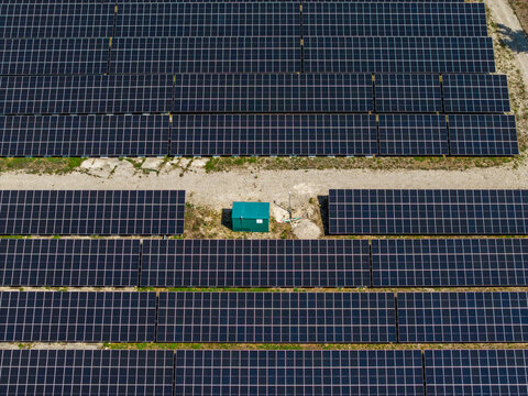 Aerial view of the Solarfeld solar farm with rows of photovoltaic panels and a small green utility box in Hombourg, Grand Est, France.