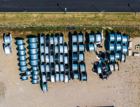 Aerial view of numerous industrial cable reels arranged in rows at the Daniken storage area, with gravel ground and a paved road nearby in Daniken, Solothurn, Switzerland.