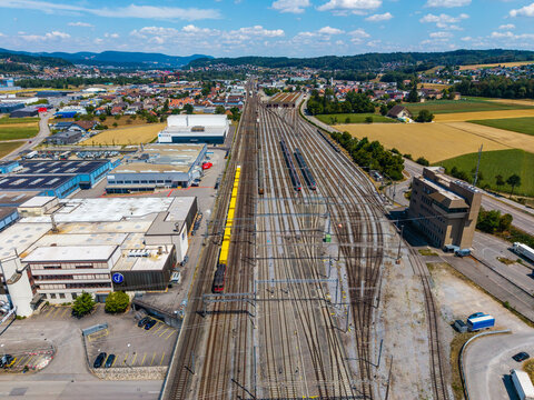Aerial view of Daniken train station with multiple railway tracks, industrial buildings, and surrounding fields in Daniken, Solothurn, Switzerland.