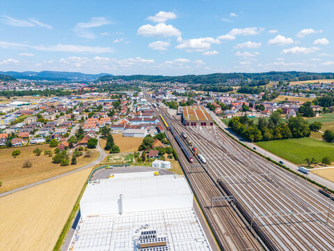 Aerial view of Daniken train station with multiple railway tracks, industrial buildings, and surrounding town landscape in Daniken, Solothurn, Switzerland.