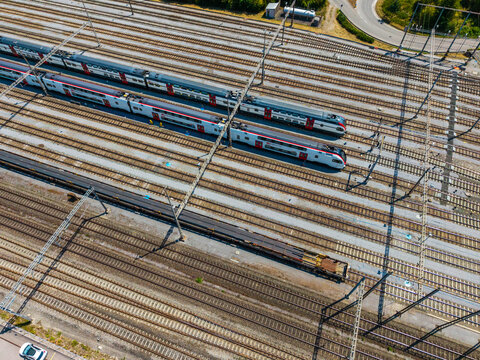 Aerial view of Daniken train station with multiple parallel tracks, modern passenger trains, and a freight train in Daniken, Solothurn, Switzerland.
