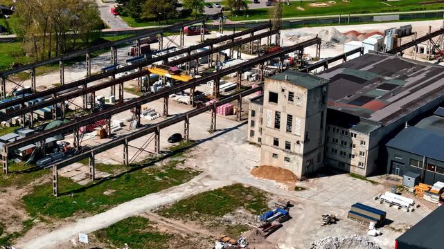 Aerial view of an industrial site featuring old buildings, metal structures, and construction materials in Riga, Latvia.