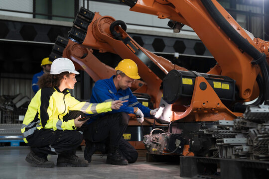 Team of engineer maintenance or repair automatic robotic arm. Group of technician discussing and inspecting automatic robot arm in industry factory