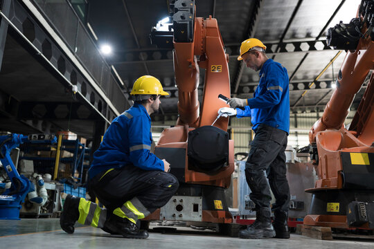 Team of engineer maintenance or repair automatic robotic arm. Group of technician discussing and inspecting automatic robot arm in industry factory