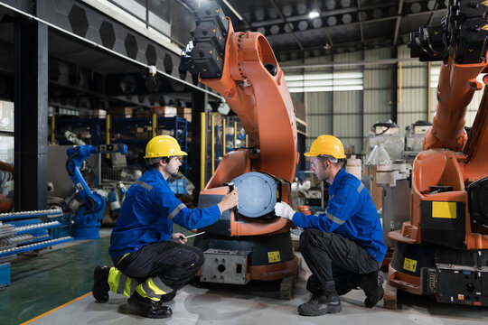 Team of engineer maintenance or repair automatic robotic arm. Group of technician discussing and inspecting automatic robot arm in industry factory
