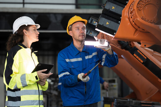 Team of engineer maintenance or repair automatic robotic arm. Group of technician discussing and inspecting automatic robot arm in industry factory