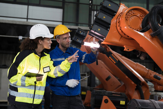 Team of engineer maintenance or repair automatic robotic arm. Group of technician discussing and inspecting automatic robot arm in industry factory