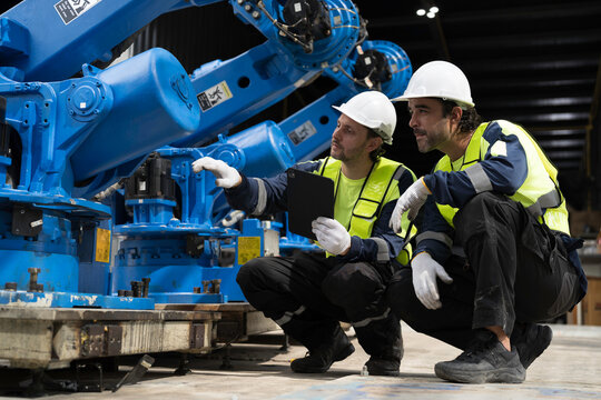 Robotics industry, training and development. Team of male engineer using digital tablet inspecting and connect to robotics arm system for testing and development solutions
