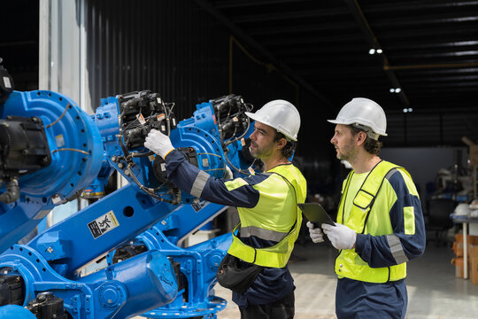 Robotics industry, training and development. Team of male engineer using digital tablet inspecting and connect to robotics arm system for testing and development solutions