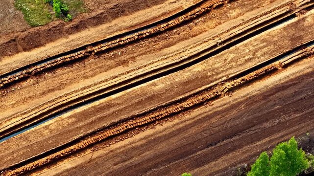 Aerial view of industrial peat extraction site with parallel trenches and tracks in Riga, Latvia.