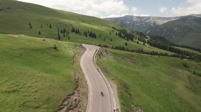 Aerial tracking shot of motorcycles riding along the Transalpina mountain road in the Carpathian Mountains	
