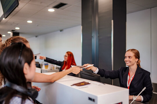Check-in agent handing boarding pass to passenger at airport counter