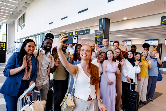 Diverse group of friends taking airport selfie before vacation flight