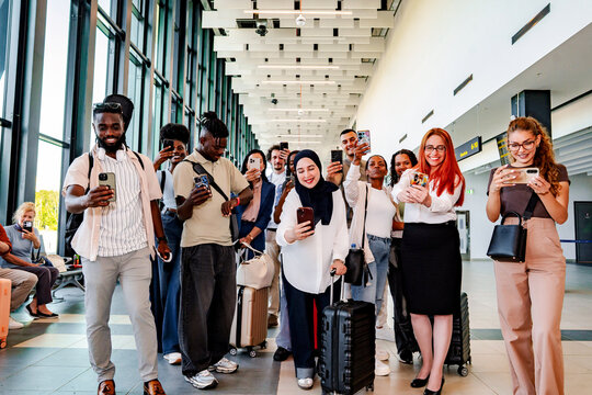 Diverse travelers taking photos with smartphones at modern airport terminal