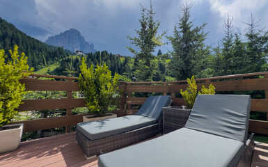 Obraz premium Awesome photo of cozy wooden balcony with comfortable lounge chair overlooking scenic green mountains. 