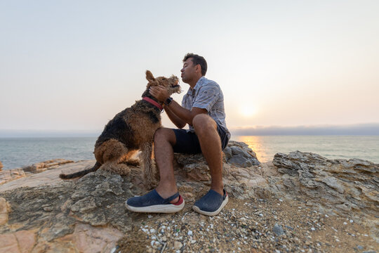 Man shares moment with dog at the coast during sunset