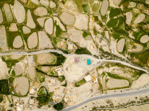 Aerial view of the arid landscape of Zanskar with terraced agricultural fields, winding roads, and small buildings in the mountainous region of Zanskar, Ladakh, India.